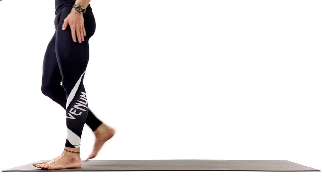 Person balancing barefoot on a wooden beam in black leggings.