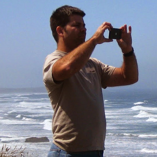 Man taking a photo at the beach on a sunny day.